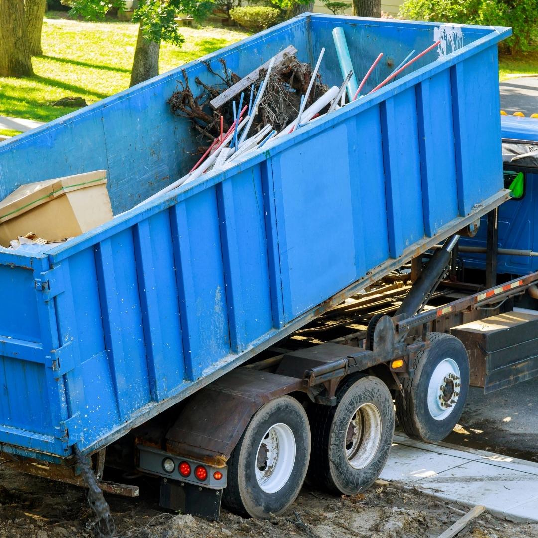 photo of a truck loading a large blue dumpster